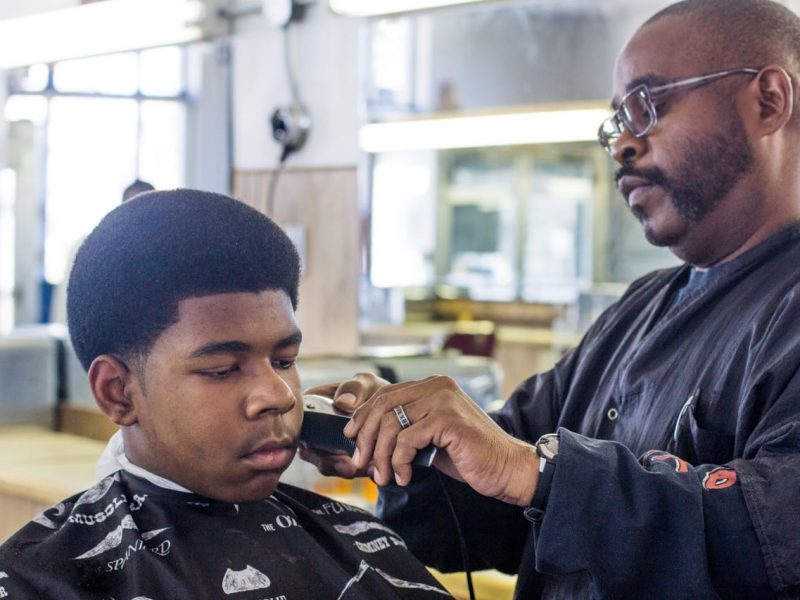 ​Lucas, 13, getting his hair cut by Metro Detroit Barber College owner Raymond Ware