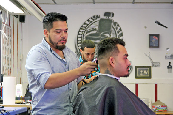 Israel Perez cutting customer's hair at The Place