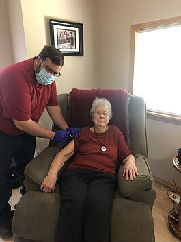 Nathaniel Bergman administers a COVID-19 vaccine in a resident's home.