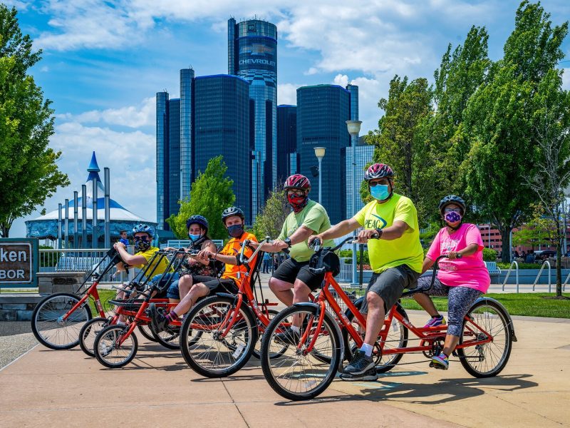 PEAC students Conor Waterman, Amanda Salinas, Owen Conley, Shawn Kohsmann, PEAC founder John Waterman, and PEAC student Tiara Sims on MoGo adaptive cycles on the Detroit Riverfront.
