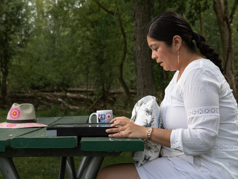 Isabel Romero looks at mementos of her family members who have died of COVID-19.
