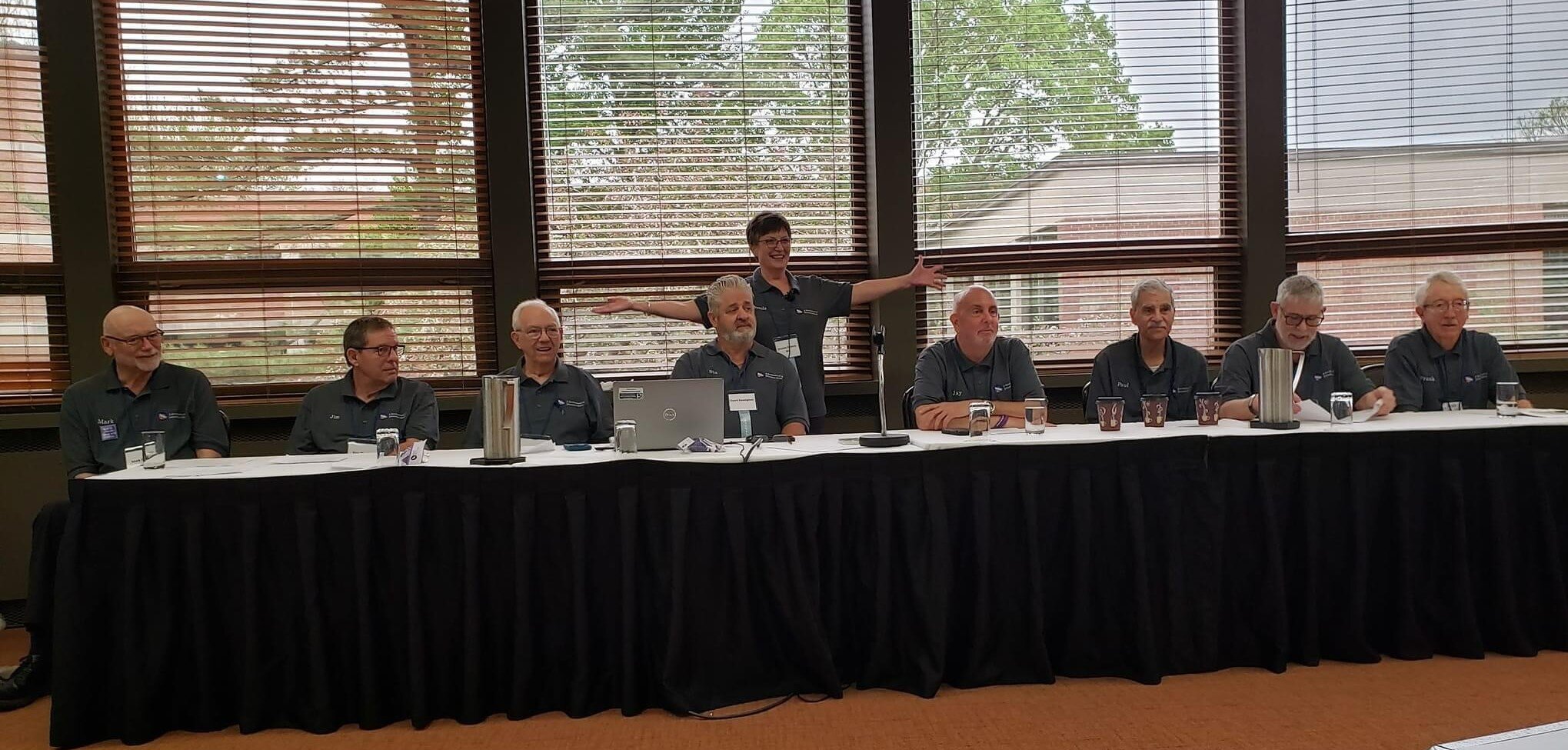 Brenda Roberts stands behind a group of Dementia Minds group members (including Mark Roberts at far left) at a public presentation.