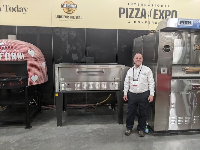 Bryan Huntley poses with a Peerless oven at the 2024 International Pizza Expo & Convention.