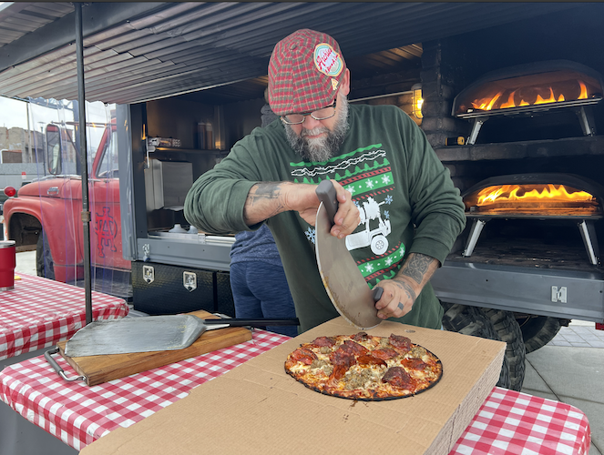 Jeremey cuts a pizza for a customer during Winter Wonderland in Sandusky in December.