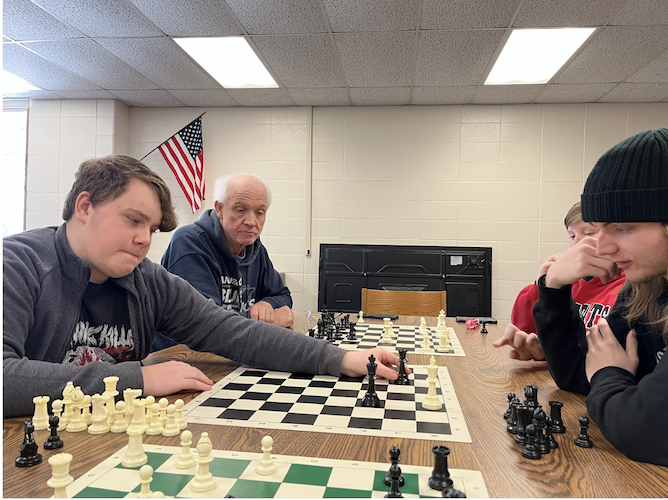 Reviewing the final moves, or ‘endgame’ of chess, Paul advises Perkins students Gage, Eli and Evan.
