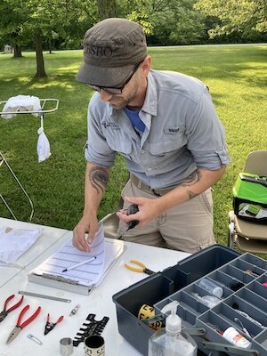 Ryan Jacob, who leads Black Swamp Bird Observatory's banding program, records weight, wing measurements, and other information about the gray catbird he is holding. (Photo/Kristina Smith)