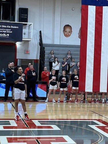 Caylin McCormick sings below a baby picture of her hanging in the Huron gym.