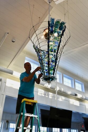 Cary Ferguson, owner of Ferguson Gallery in Lakeside Marblehead, meticulously hangs over 250 pieces of hand blown glass on a chandelier in his new venture, the Beach Glass Lounge, due to open soon in the 5000 block of East Harbor Road.