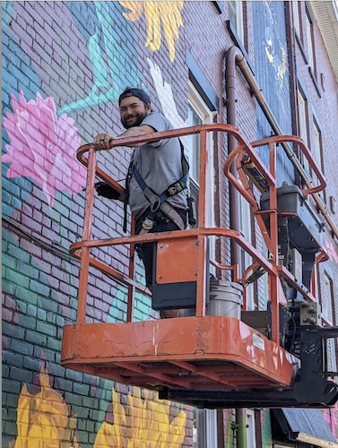 Brennan paints a flower as part of the nature-themed mural. (Photo/Courtesy of Derek Brennan)
