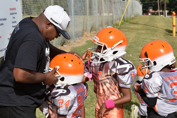 Antonio Huntsman, founder and coach of the Orange Mound Raiders helps a young football player with his helmet as he prepares to take the field for a Saturday morning game.
