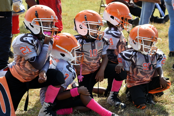 Young athletes wait and watch on the sidelines as their teammates tackle, run and kick during a Saturday morning football game. The young men cracked jokes and gave each other playing advice during the game.