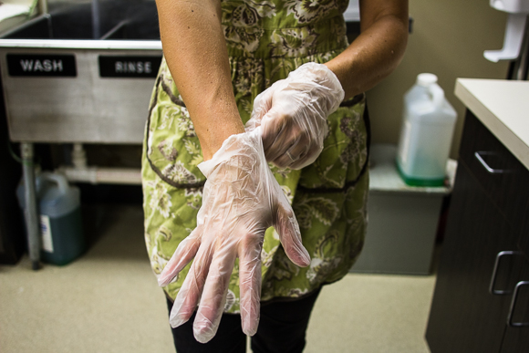 Kristin Fox-Trautman puts on gloves before preparing dishes for her food truck Inspire Community Cafe.