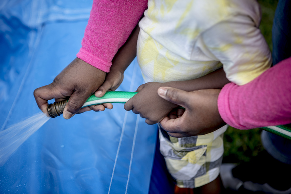 LaTonya Taylor, of Epic Bouncing, and her son Michael, 3, fill up the pool of the bounce house while setting up in a client's yard.