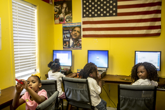 Jamiya Richmond, 6, plays a recorder while other kids play in the computer lab at the Vance Avenue Youth Development Center.