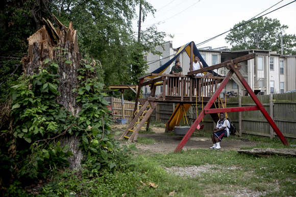Kids hang out on the playground near a tree that fell following a late May storm at the Vance Avenue Youth Development Center.