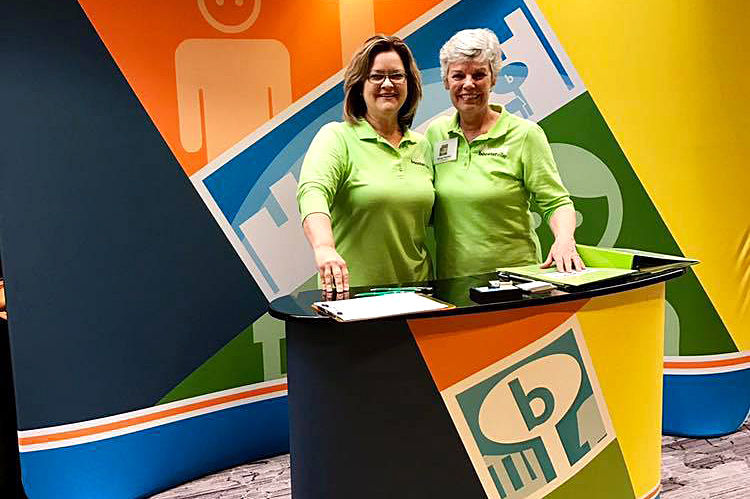 Pam Cooper, left, and Ginny Parker promote Boosterville at the Indiana PTA convention in early May. The Coopers have a strategic relationship with the National Parent-Teacher Association and have loaded in 32,000 PTAs across the country in the Boosterville app.