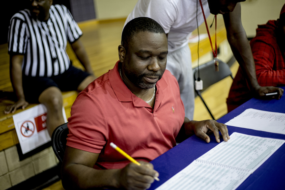 Charles Banks, a family enrichment counselor with the Neighborhood Christian Center's Legacy Men's Ministry, keeps score at the table during a basketball game at the center's gym.