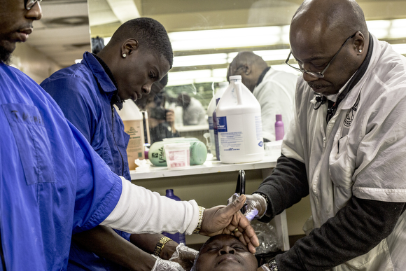 Torrus Brooks (R) the administrative owner at The Barber School on Jackson Avenue in Klondike, helps students with a client.