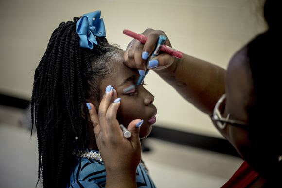 At a final dress rehearsal at the Dave Wells Community Center, Eriany Brown, 8, gets help with makeup from her coach Keisha Moss before a performance with their majorette team Diva Sensations.