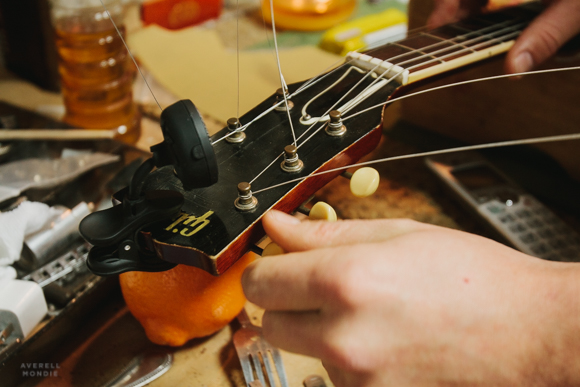 Hans Hilboldt adjusts the tension of the strings on a guitar.