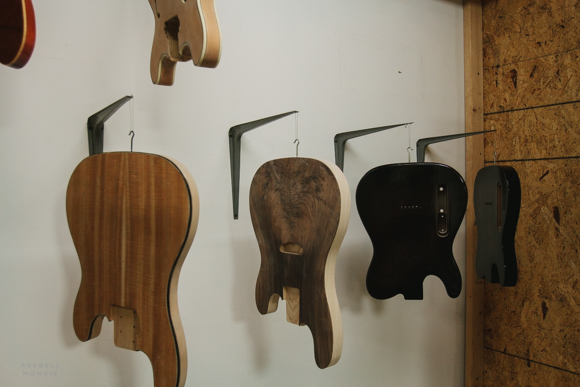 Guitar bodies hang in the workshop waiting to be connected with necks.