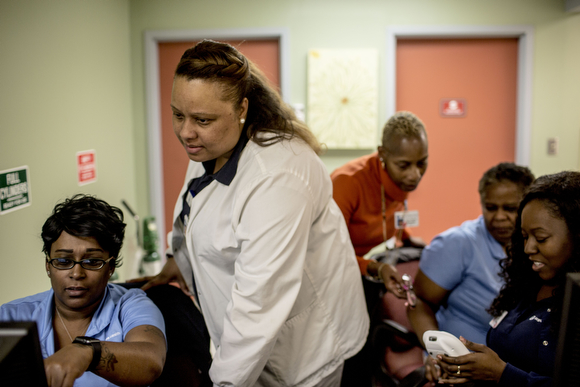 The nurses and support staff gather around the nursing station at the Guthrie Primary Care Clinic in Smokey City.