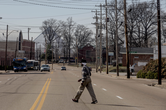 A man walks across Jackson Avenue near the edge of the Smokey City neighborhood with Uptown.