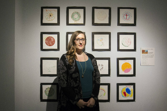 Paige Scheinberg stands in front of mandalas created in an art therapy session.