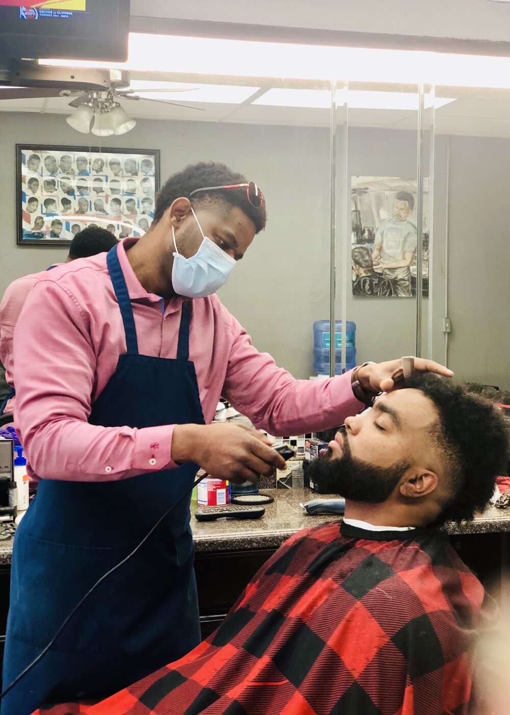 “I’ve been knowing him for 17 years,” says Jaquavis Surney, pictured here in the barber’s chair. “He’s been cutting my hair for that long, and now he’s cutting my kid’s hair.”