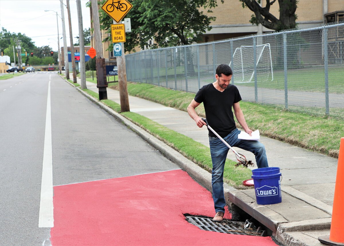 Dane Forlines of the Heights CDC clears debris from a storm drain near the bioswale. (Reginald Johnson) 
