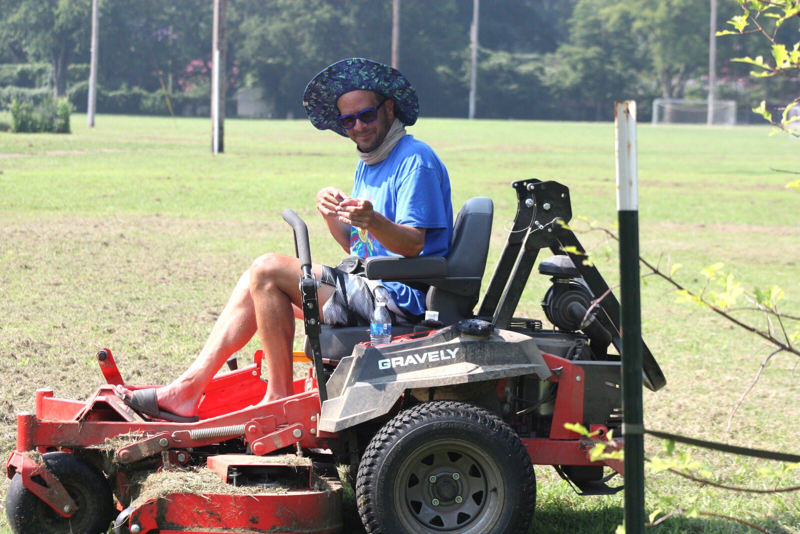 Chris Collier, founder of Friends of Gaisman Park, takes a break from cutting the park's roughly 17-acre field to pose on the organization's new riding lawnmower. (Cole Bradley)
