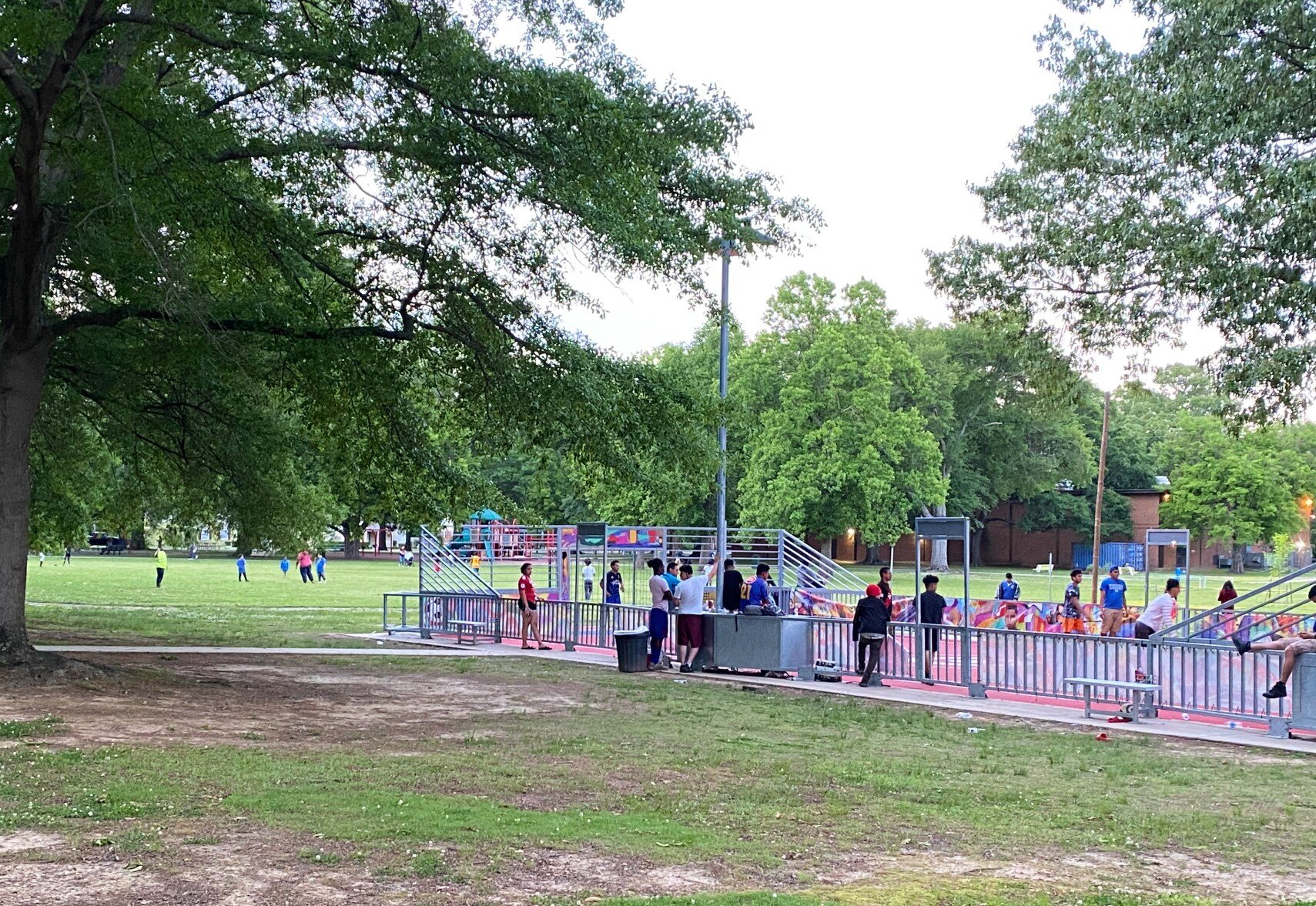 At Gaisman Park, a Friday night pickup game draws spectators. In the background families play games in the field in front of Gaisman's playground. The new mini-kick soccer court was sponsored by the U.S. Soccer Foundation and Target. May 2021. (Cole Bradley) 