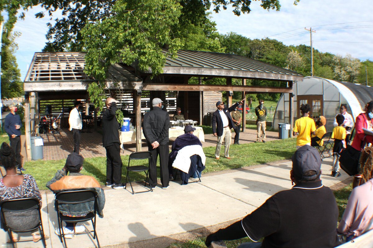 Knowledge Quest Executive Director Marlon Foster (center) points to various KQ properties around the Green Leaf Learning Farm, including the dormitory for college students and a recently acquired corner store. (Cole Bradley)