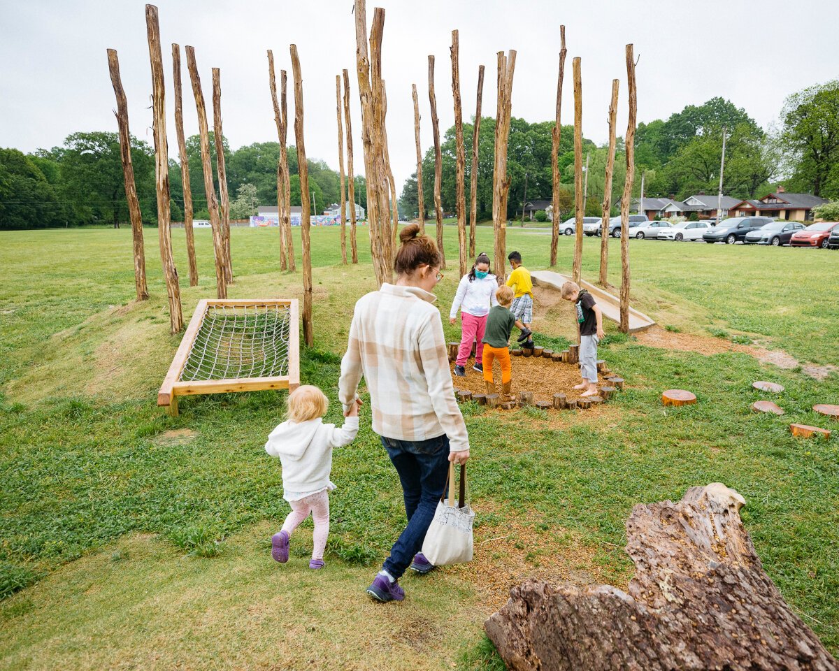 Treadwell Elementary students and families explore the new features of the Treadwell Park nature playground, including a faux-forest made of locust poles, hollowed log tunnel, wooden benches that double as balance beams, and rope ladder. (Ziggy Mack)