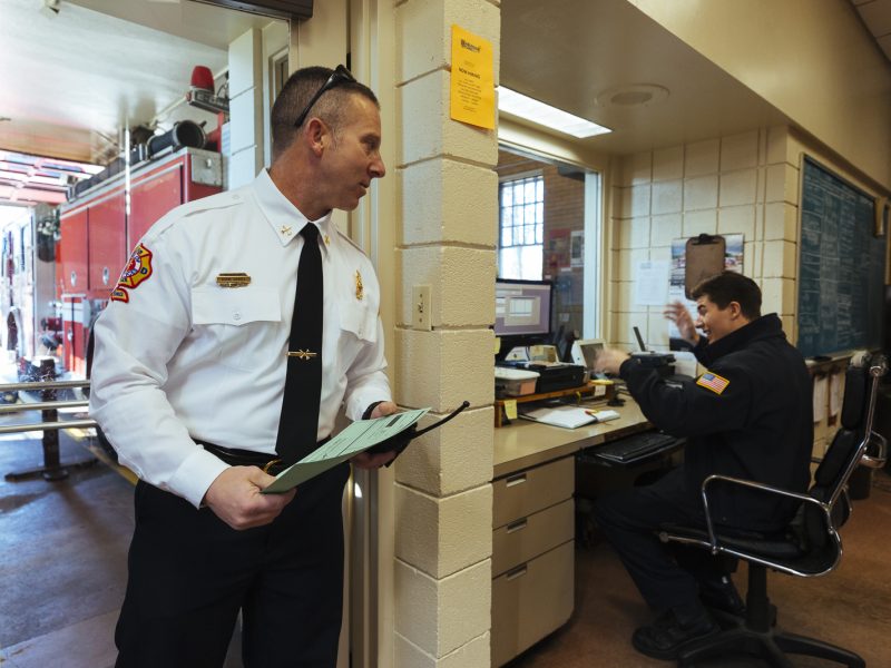 Twenty-year veteran Shane Howell (left) stops by with paperwork as Private Michael Pence (right) works the Station 18 desk where crew members field emergency calls and help citizen who walk in with an emergency. (Ziggy Mack)