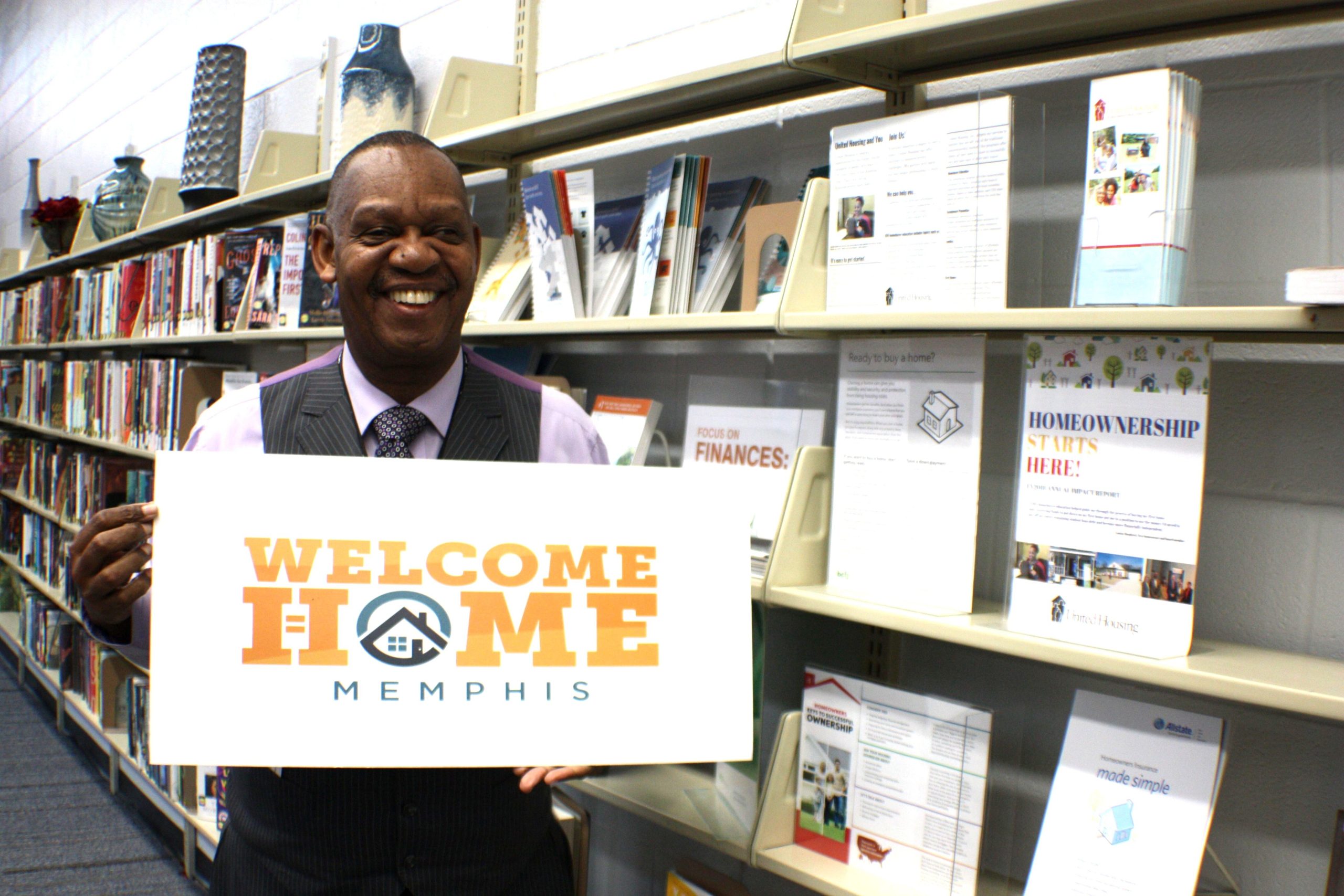 Earnest Shinault, Crenshaw Library's adult services librarian, holds a sign he uses to attract library patrons to the financial literacy and housing resources at the branch. 2019. (Cole Bradley)
