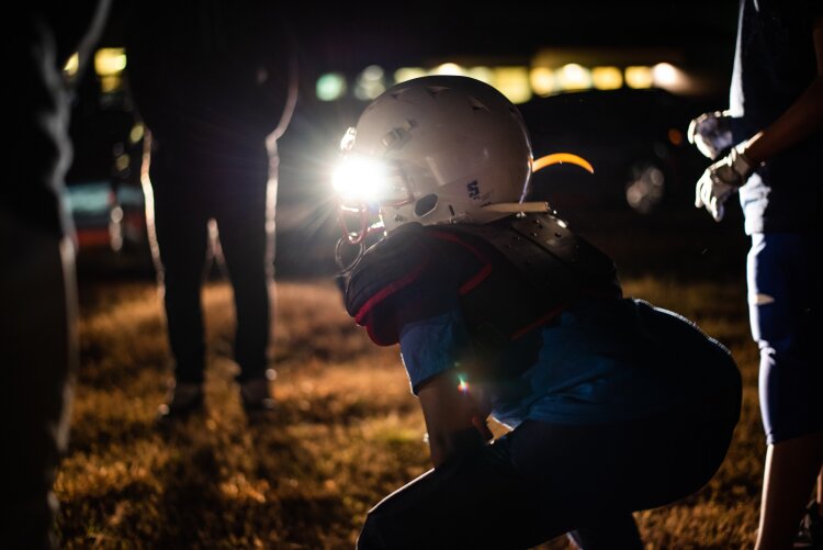 Headlights shine through Delvonte Watson's visor as he awaits the snap at the Ridgeway Cougar's pee wee football practice, 2019. (Malik Martin) 