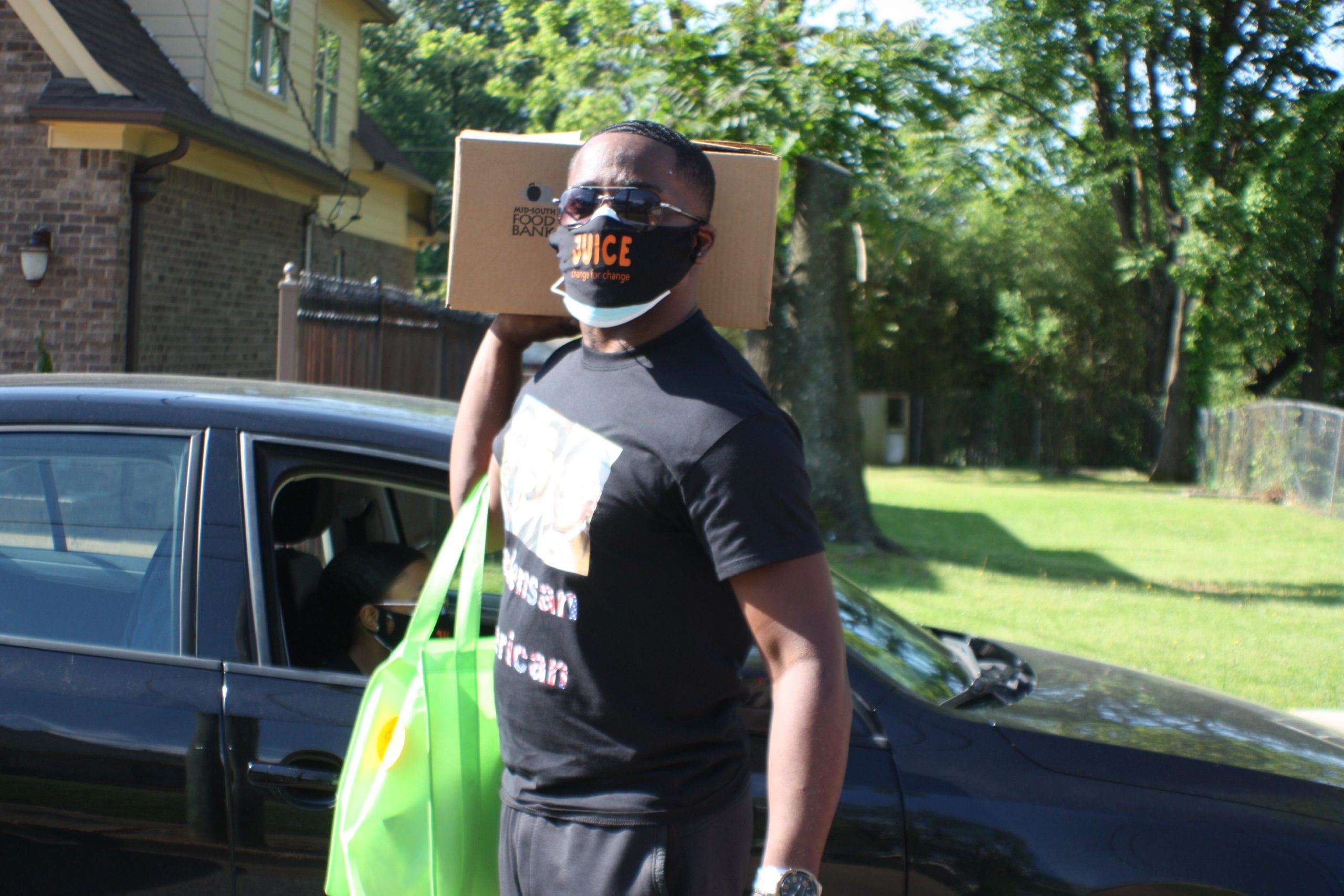 Justin George, a member of the Orange Mound Millennials, volunteers with the JUICE Orange Mound CAREavan. He walks to a neighbor's house with a personalized care package wearing a custom JUICE Orange Mound face mask for safety. (Cole Bradley)