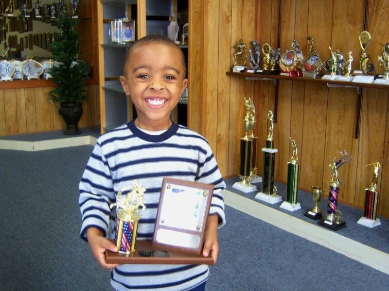 A child proudly displays an award at C & J Trophy and Engraving, located at 3444 Park Avenue in the Orange Mound-University District area. The business has been open since the 1970s. (C & J Trophy and Engraving)