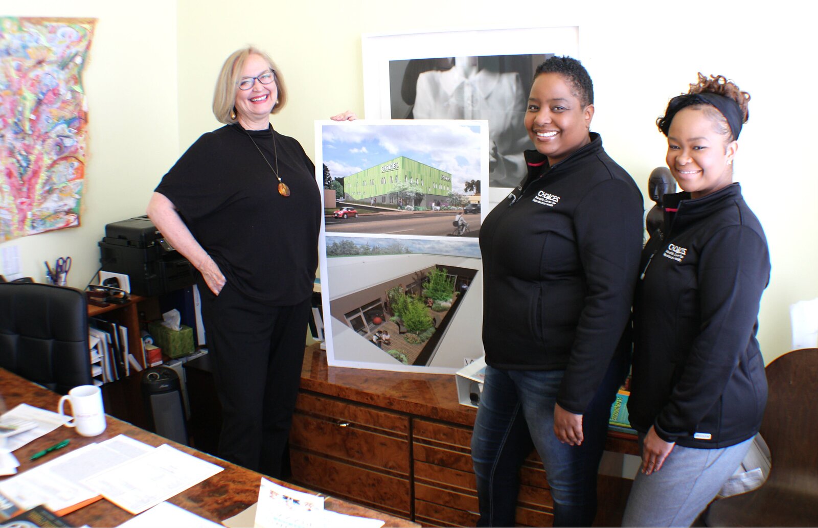 L to R: CHOICES Executive Director Rebecca Terrell, CNM and Director of Midwifery Nikia Grayson, and CNM Kemetra King stand in Terrell's office. They proudly display a rendering of the new full-spectrum reproductive health center and the luxurious garden courtyard attached to its birth suites. (Cole Bradley)