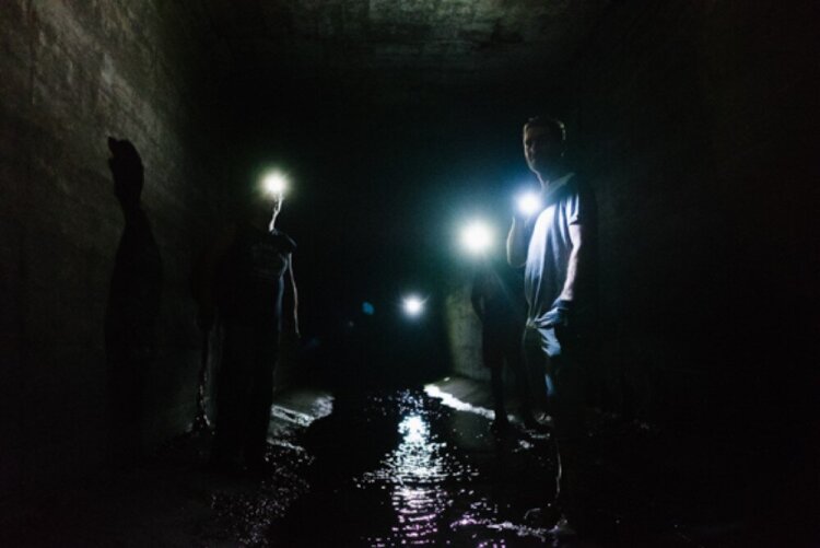 Four urban explorers make their way up the Gayoso Bayou, navigating by flashlight. The Gayoso Bayou was once meandered through the Uptown area and was believed to be an important place for baptisms. It is now contained underground. (Brandon Dahlberg) 