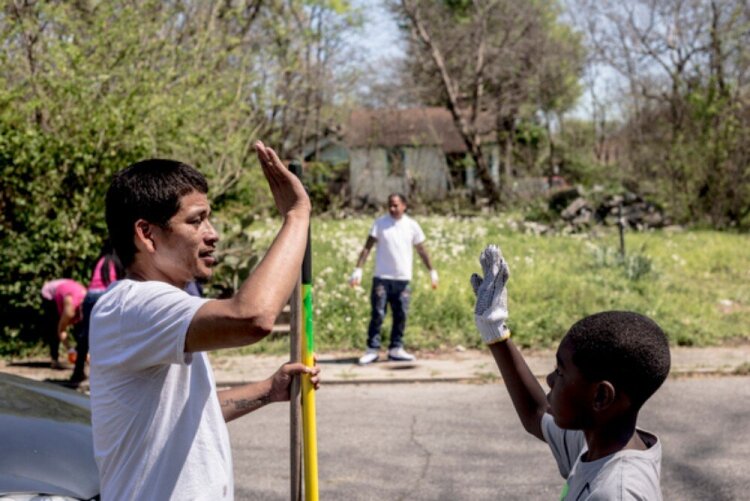 Jason Ayers (L) high fives his cleanup partner. Crowning Our Youth, Inc., an anti-violence youth-oriented group, helped clean up vacant lots along Randle Street in Klondike. (Andrea Morales) 