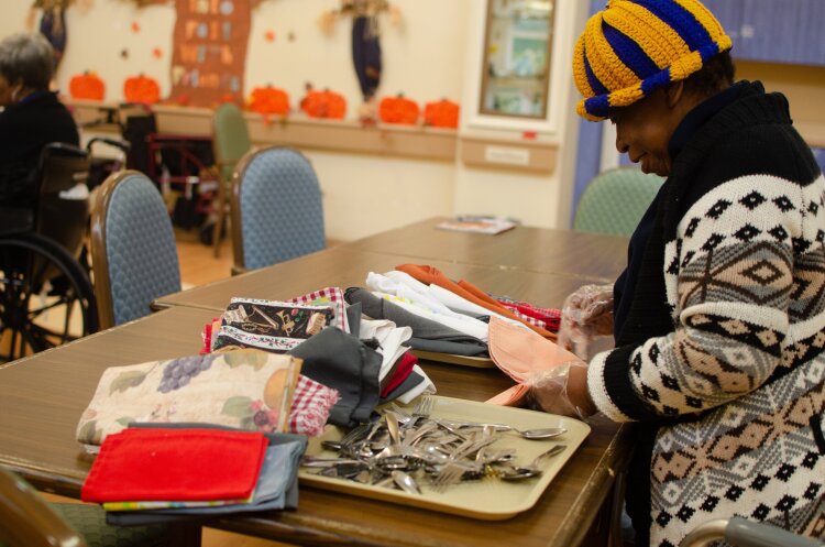 Kay attends the Dorothy's Place day program for people with Alzheimer's and Dementia. Here she sorts and folds clothes and pieces of fabric keep her basic self-care skills sharp. (High Ground News, Cat Evans) 