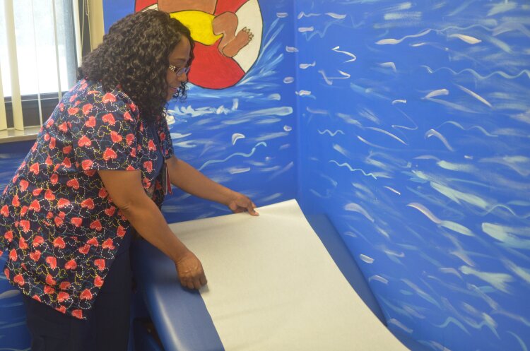 School nurse Patricia McCraw prepares the exam table for the next student she'll see at A.B. Hill's nurse's clinic. The brightly painted walls put students at ease as McCraw treats what ails them. (Cat Evans)