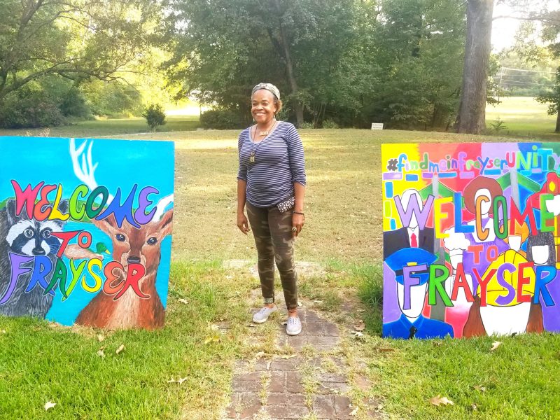 Frayser Local Arts Festival organizer Lurlynn Franklin stands next to two of five 'Welcome to Frayser' paintings. She designed the signs as paint-by-numbers and more than 700 Frayser residents had a hand in filling them in. (Arkwings Foundation)