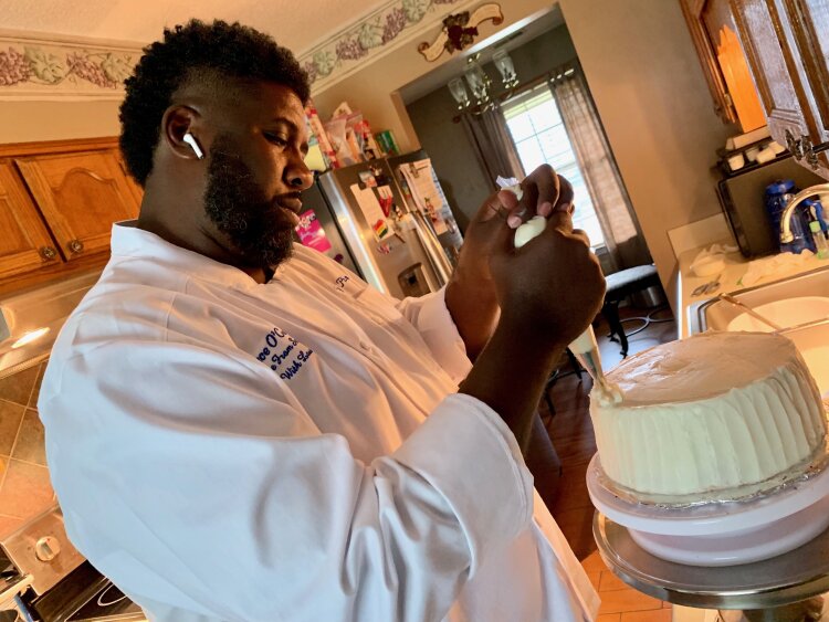 Chef Lee Phillips decorates a red velvet cake with cream cheese icing. (Cat Evans)