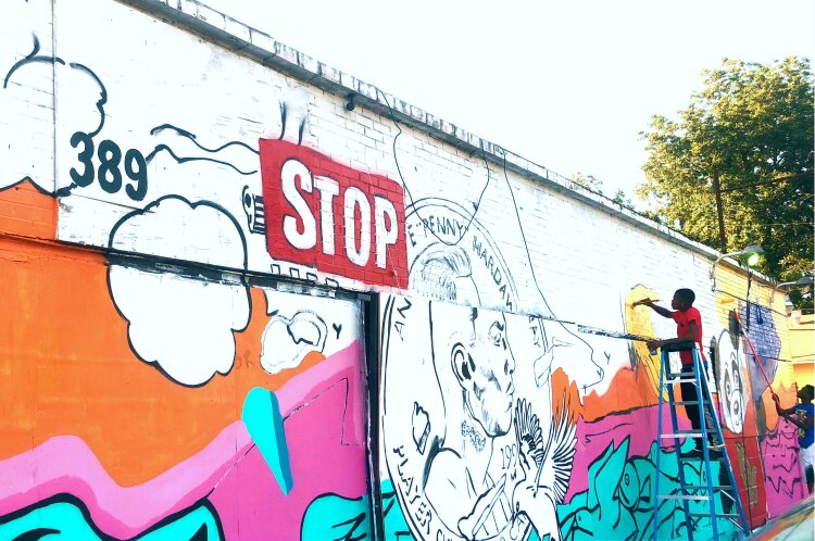 Terry Rogers (L) and Donte Davis (R) are part of the Carpenter Art Garden's Mural Apprenticeship Program. This mural is located at You's Grocery on Scott Street and funded by the Urban Arts Commission's Neighborhood Art Initiative. (AJ Dugger)