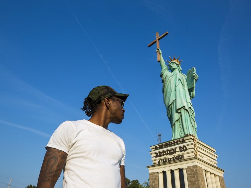 Tre Young plays Pokemon Go on the sidewalk near World Overcomers Church at 6655 Winchester Road. Behind him stands the church's Statue of Liberation through Christ. (Ziggy Mack)