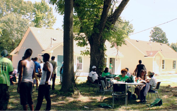 Guests of the Frayser CDC open house celebration ate Crutchfields Bar-B-Q and mingled in the shade. Behind them, two of the three newly built houses were open for tours. (Cole Bradley)