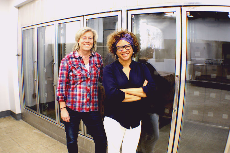 Dr. Heather Jamerson (L) and Diane Terrell (R), cofounders of 275 Food Project, stand in front of a cooler at the New South distribution headquarters at Harbor Landing. The coolers were discovered after removing years of stored items from the space. (Cole Bradley)
